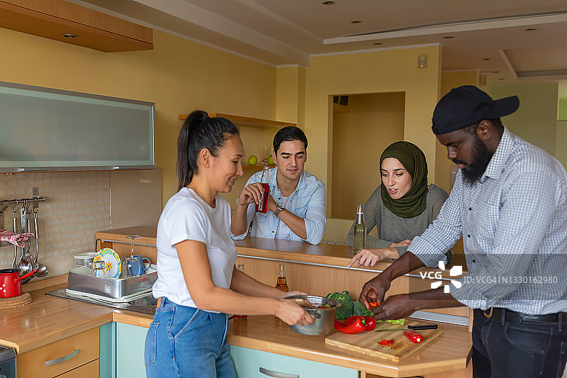 兴奋的多元文化朋友们在家玩乐并准备美味佳肴图片素材