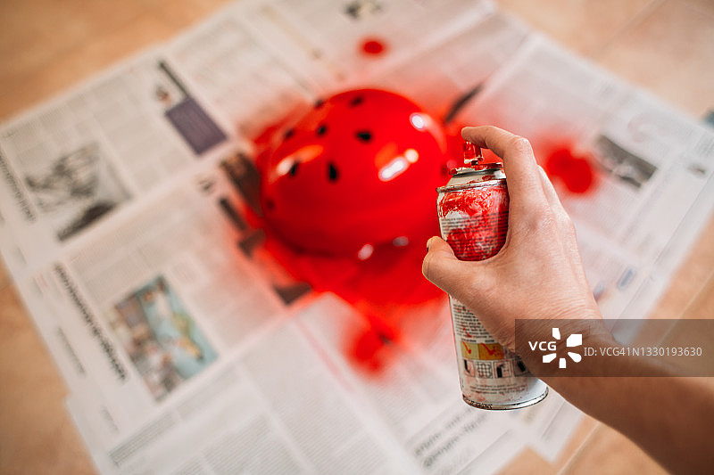 女人用红色喷漆涂头盔图片素材