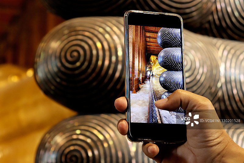 用智能手机拍摄泰国寺庙的年轻旅行男人图片素材