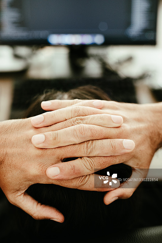 一个感到压力的男人在使用电脑工作，并抱着头图片素材