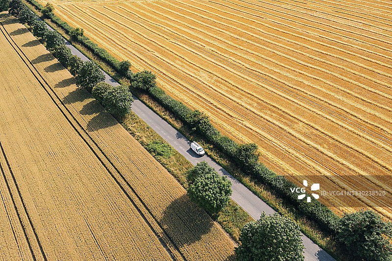 在穿过农业用地的乡村道路上的白色厢型车图片素材