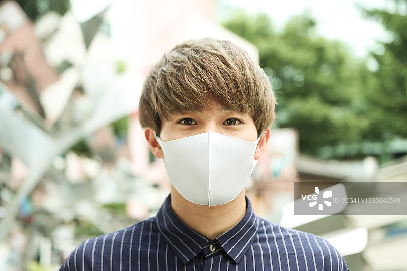 戴防护口罩的微笑亚洲青年男子肖像图片素材