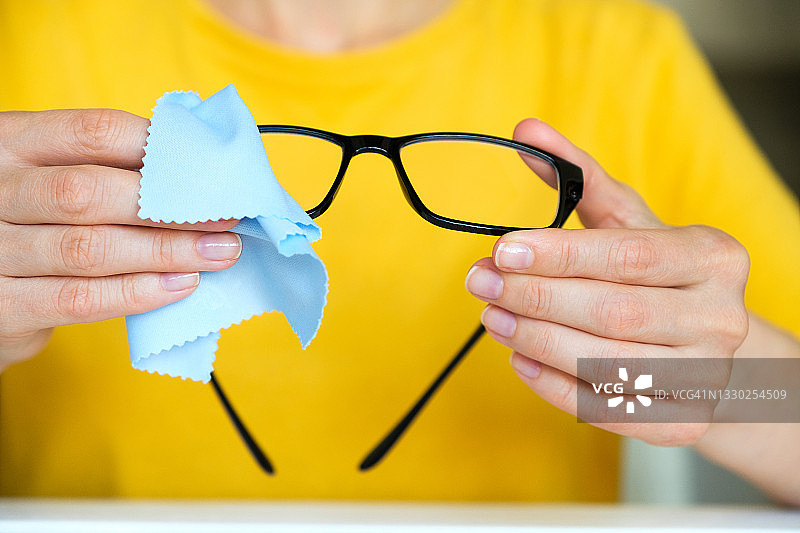 女孩擦拭眼镜上的灰尘图片素材