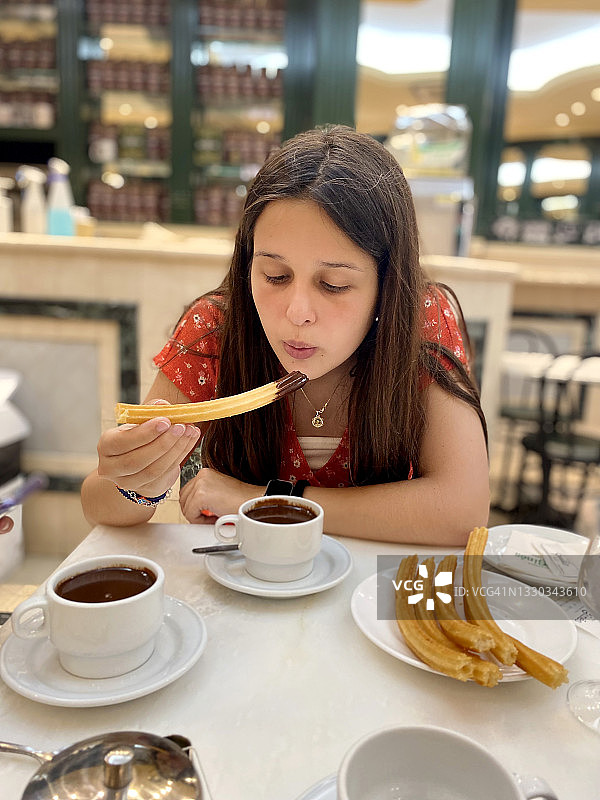 正在吃巧克力和西班牙油条的年轻西班牙裔女子图片素材