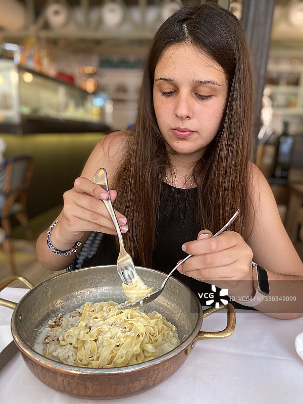 正在吃卡门培尔干酪意大利面的西班牙裔年轻女子图片素材