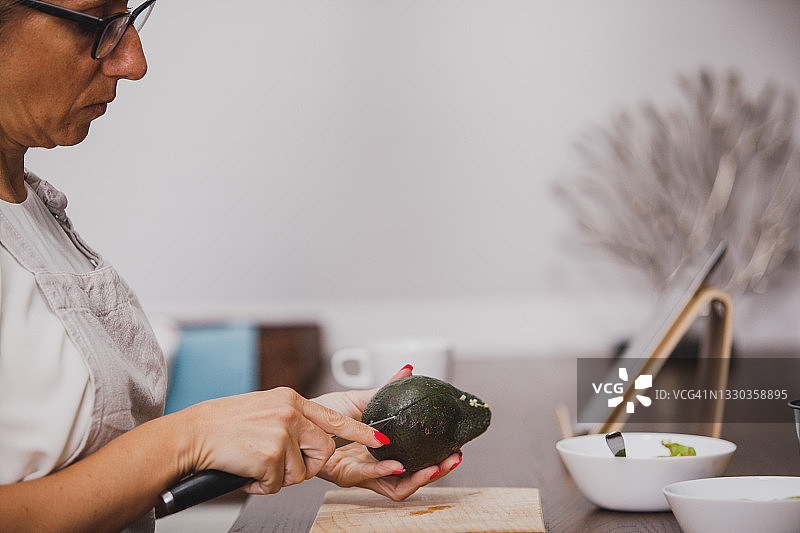 侧视图：女子将牛油果切成两半图片素材