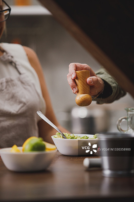 男人在妻子准备的鳄梨酱中加盐图片素材