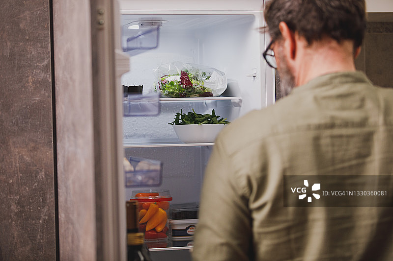 男子站在打开的冰箱前的背影图片素材