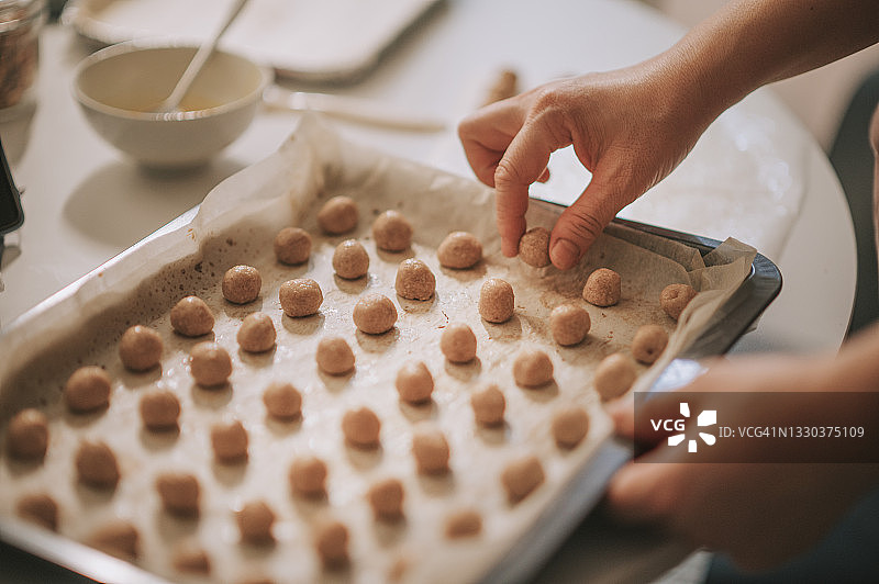 特写：亚洲中年女性在家中厨房烤盘上摆放花生饼干图片素材
