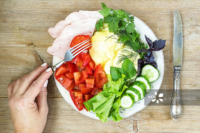 女人手拿盘中番茄黄瓜火腿煎蛋卷图片素材