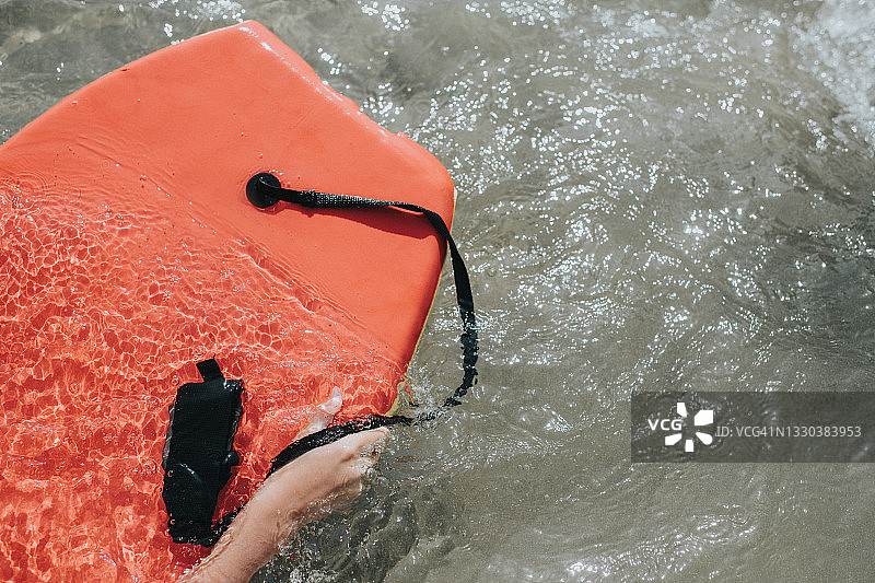 儿童抱着冲浪板在海水中图片素材