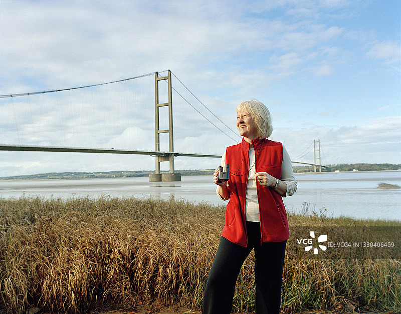 在桥边用双筒望远镜观察的女人图片素材