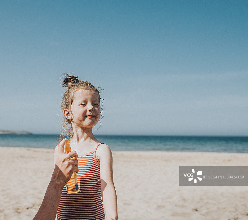 成人为可爱小女孩涂抹防晒霜图片素材
