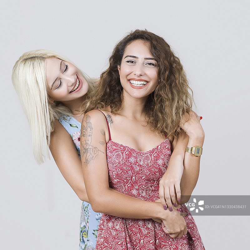 年轻漂亮的棕发和金发姐妹拥抱的肖像图片素材