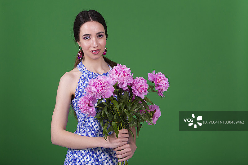 快乐的年轻女人拿着一束粉红色的鲜花图片素材