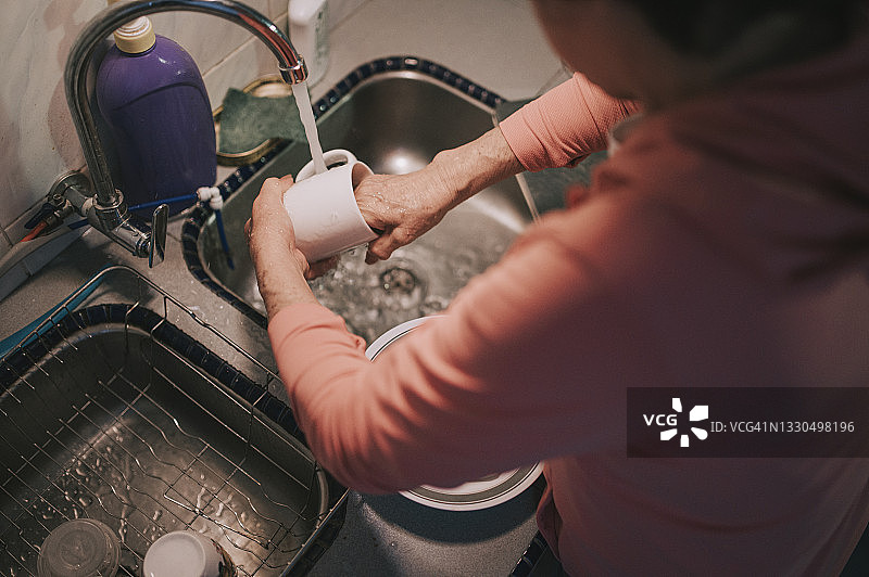 俯视图亚洲妇女洗碗后，在厨房晚餐杯图片素材