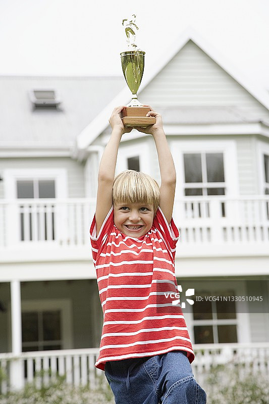快乐的男孩展示足球奖杯图片素材