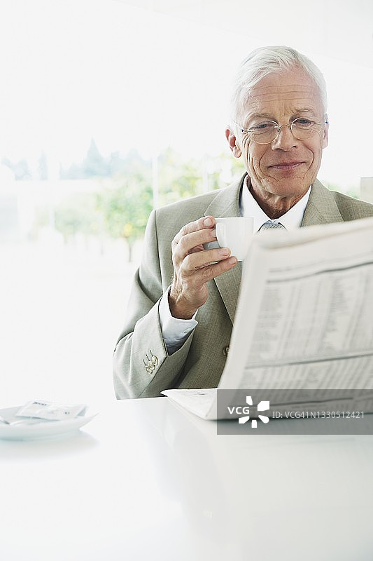 年长的商人喝咖啡看报纸图片素材