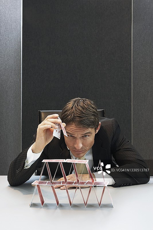 商务人士在办公桌上搭建纸牌屋图片素材