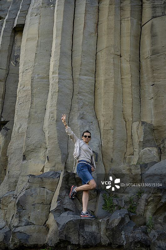 在日落的光线下，站在钴蓝色柱子旁的戴太阳镜的女人图片素材