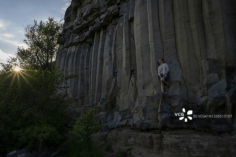 坐在玄武岩柱悬崖上欣赏美丽风景，充满灵感和动力的女人图片素材