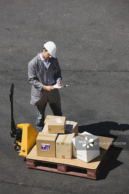 工人在工厂检查货物，手持剪贴板图片素材