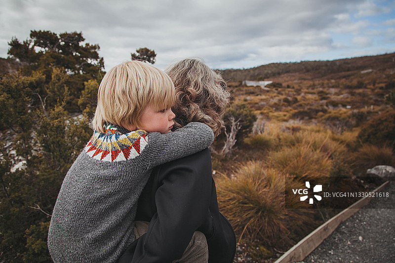 祖母背着孙子在灌木丛中行走图片素材