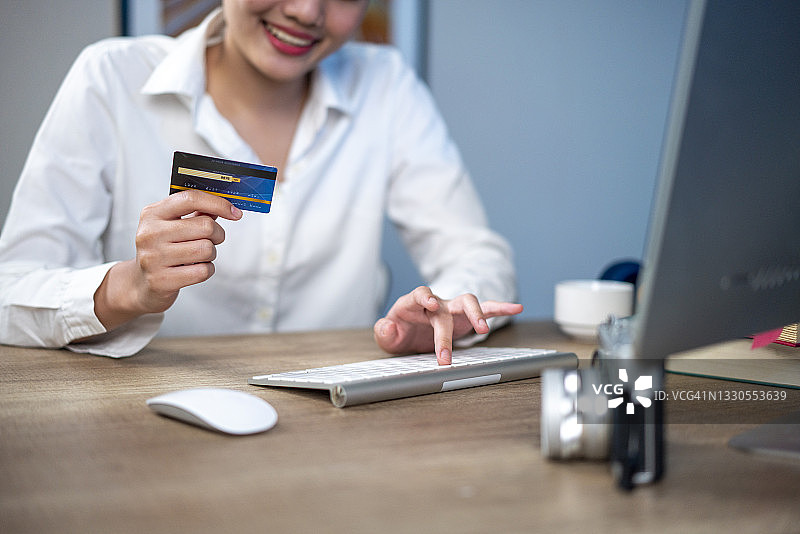 一位身份不明的人在家中手持信用卡对着笔记本电脑图片素材