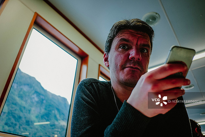 拿着手机，对着镜头面露惊恐的中年男人图片素材