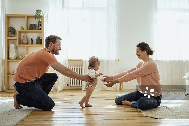 父母帮助女儿在家走路图片素材