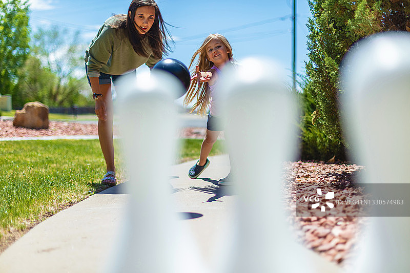 千禧一代母亲和女儿在人行道上打保龄球照片图片素材