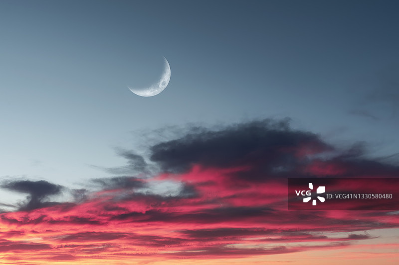日落时分带有新月状的蓬松粉色、紫色和灰色云朵，积云拥挤图片素材