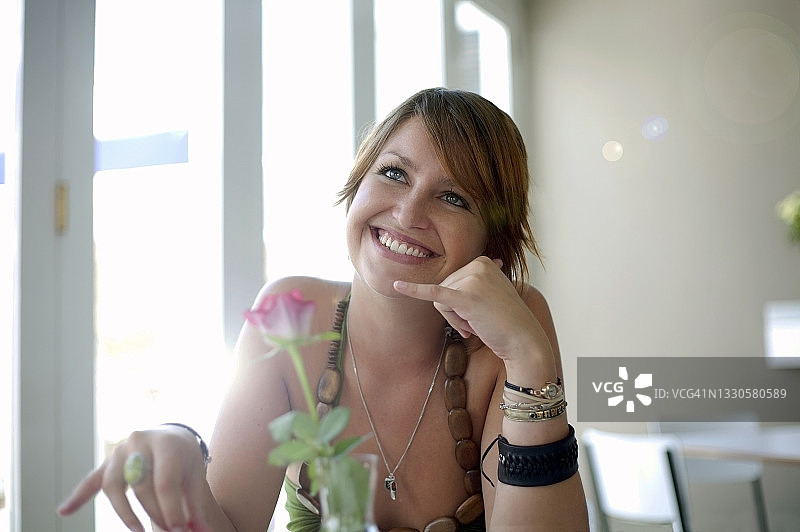 快乐的年轻女子在餐厅做出给我打电话的手势图片素材