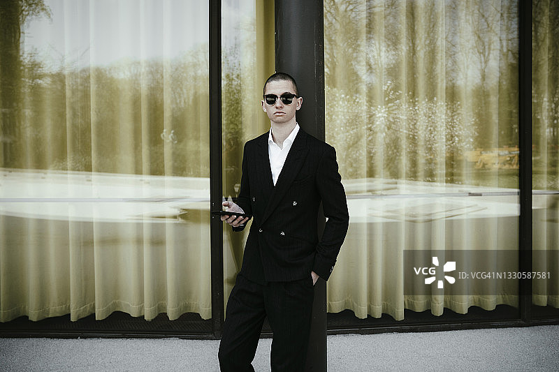 商人手持手机站在窗前图片素材