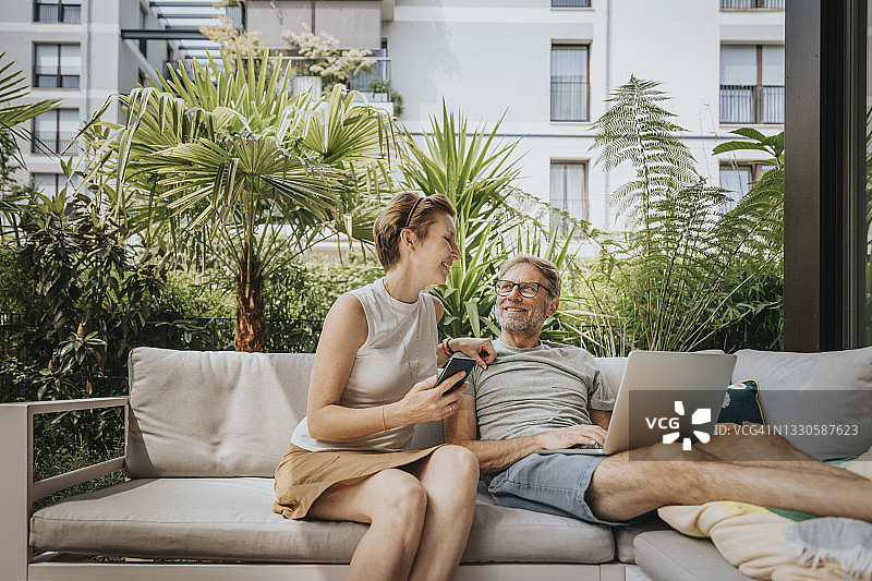 笑容满面的女人坐在沙发上和男人聊天图片素材