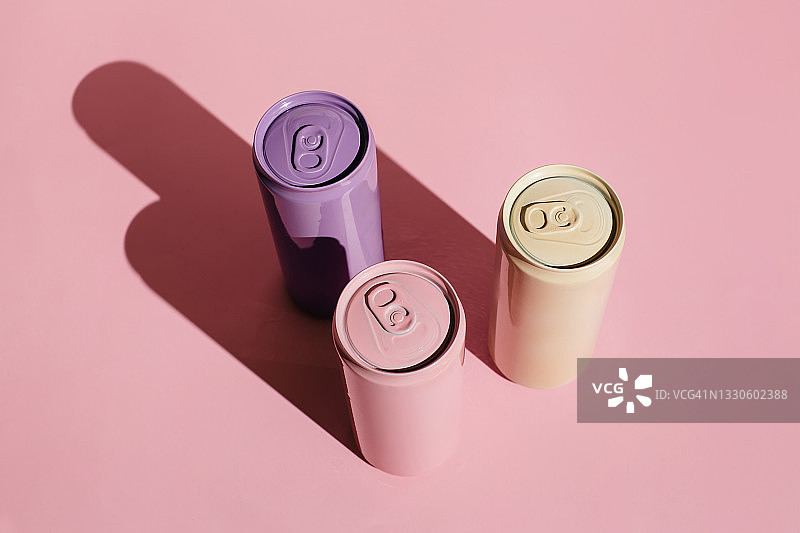 粉色背景上的粉色、米色、淡紫色铝制饮料罐。极简创意静物。零浪费，无塑料概念。平铺，顶视图。图片素材