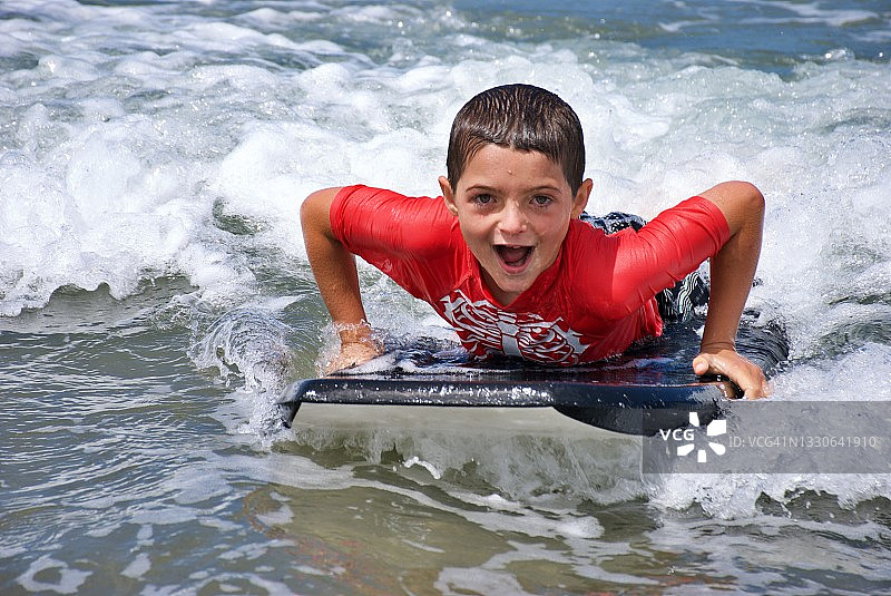 夏天在海中玩趴板的年轻男孩图片素材