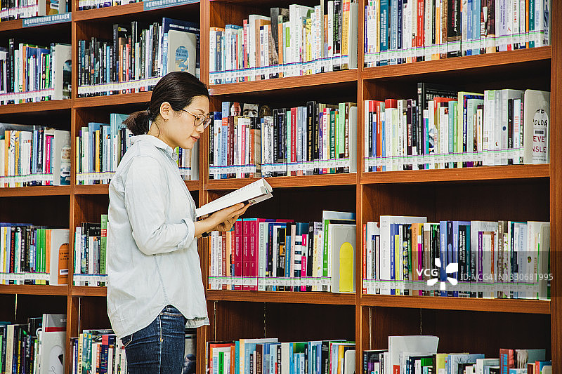 在图书馆看书的亚洲女大学生图片素材