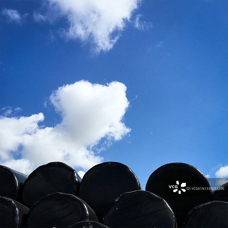 黑色青贮饲料包图案后的蓝天白云图片素材