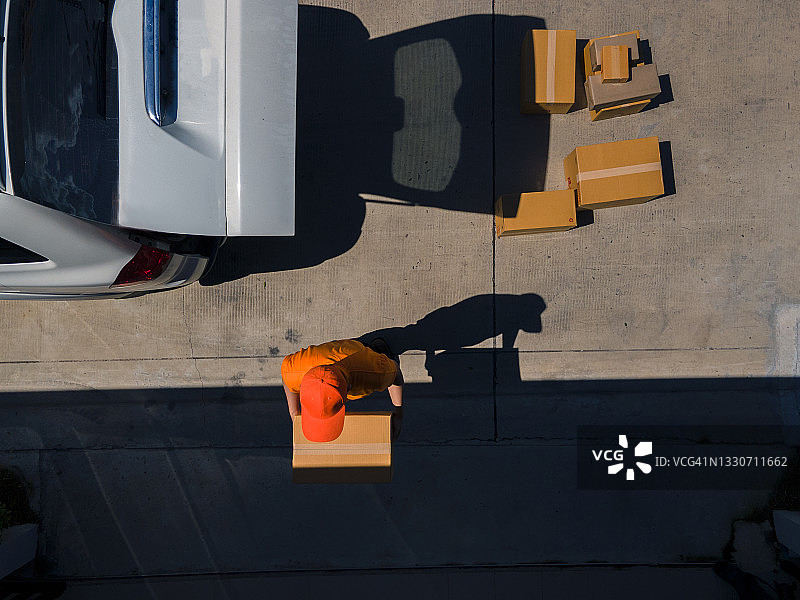 送货员从送货车上卸下纸板箱的上方镜头图片素材