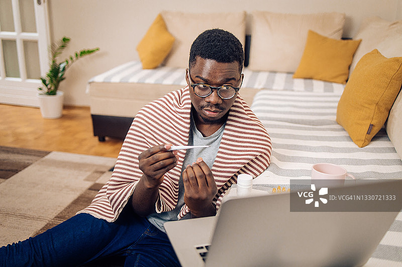 年轻的非裔美国男子测量体温并进行在线医疗检查图片素材