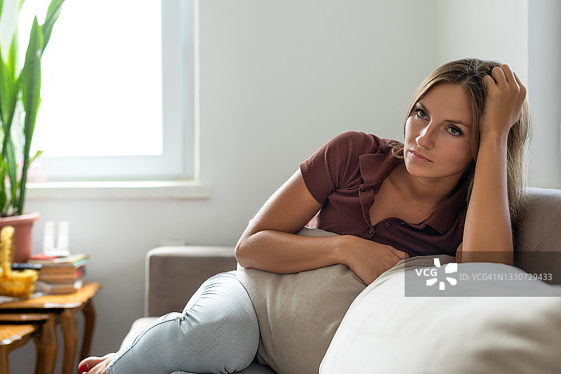 悲伤的女人独自坐在家中的沙发上图片素材