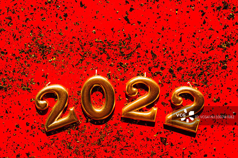金色2022数字俯视图，放置在闪亮五彩纸屑上，新年主题，橙色背景图片素材