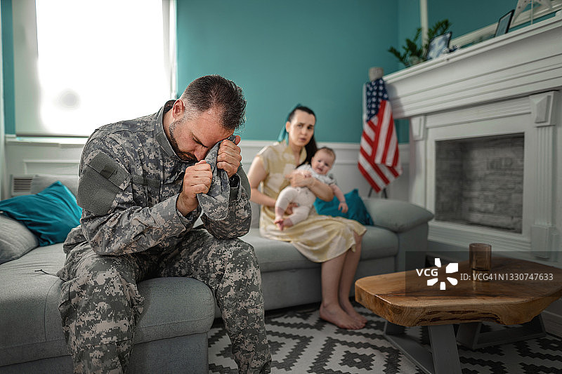 沮丧的士兵和家人一起坐在沙发上图片素材