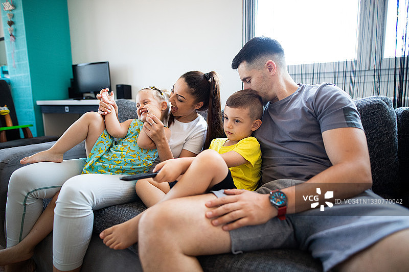 在沙发上和两个孩子一起的快乐家庭图片素材