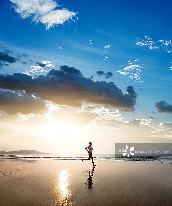 男人在日落时分的海滩上慢跑图片素材