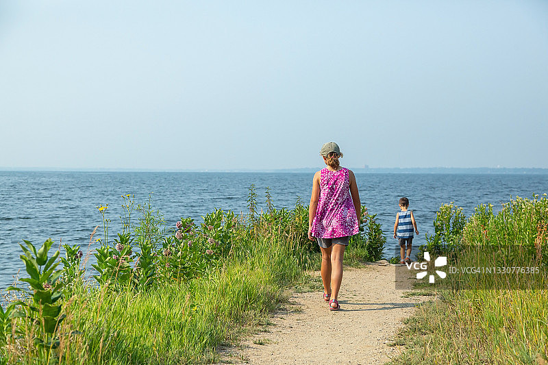 夏季在湖岸小路上行走的男孩和女孩图片素材