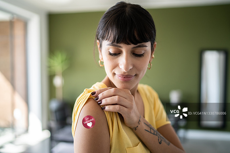年轻女子展示带有疫苗接种贴纸的手臂图片素材