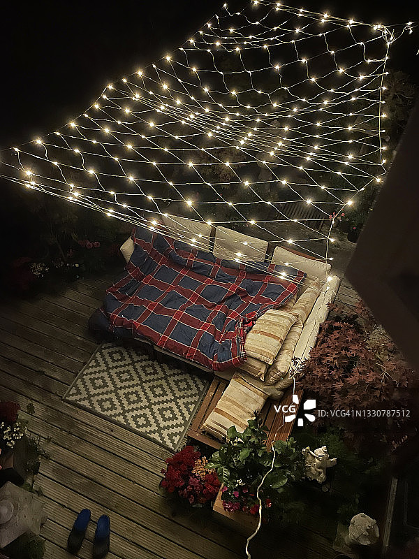 夜晚的户外休闲区，灯光、坐垫和盆景树图片素材