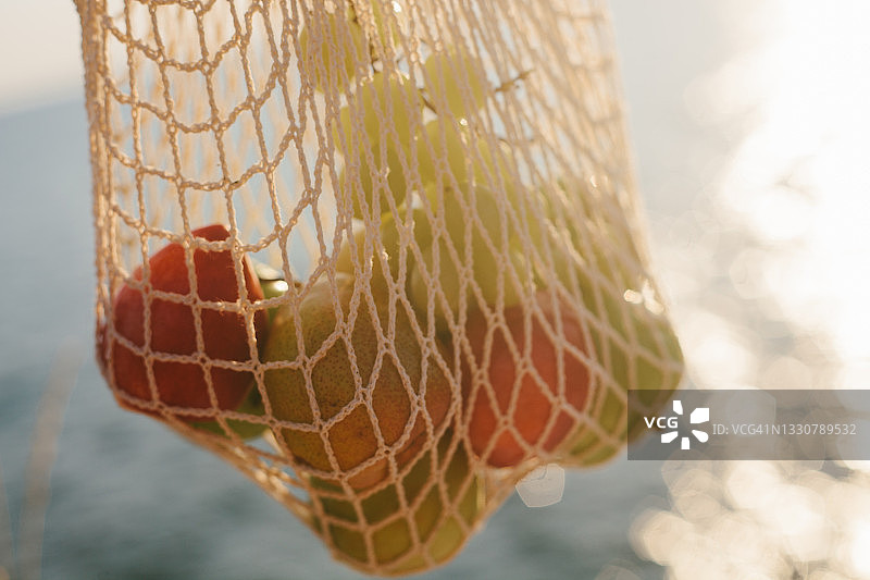 蓝色大海背景下的夏季水果网袋特写图片素材